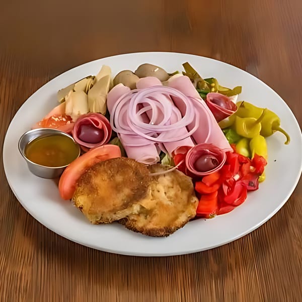A white plate filled with various antipasto items, including meats, cheeses, and pickled vegetables.