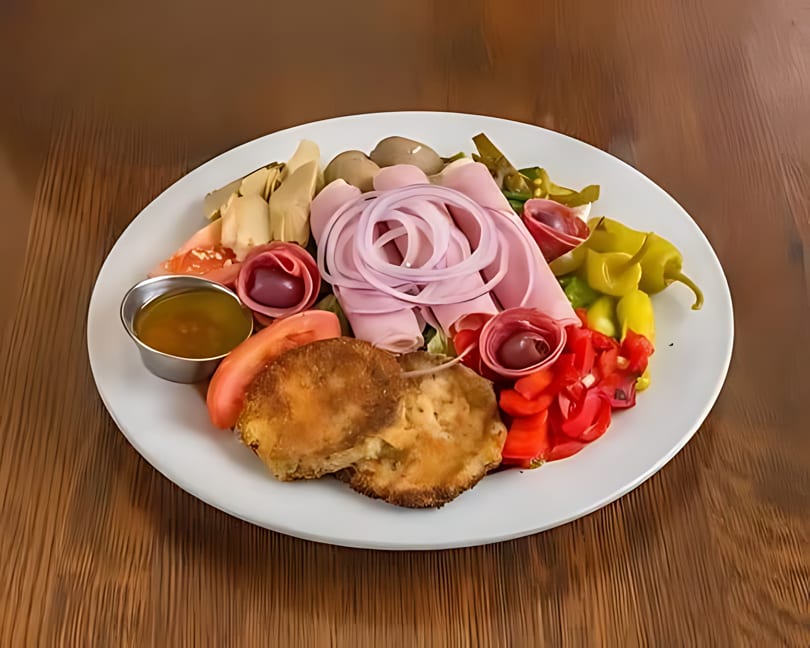A white plate filled with various antipasto items, including meats, cheeses, and pickled vegetables.