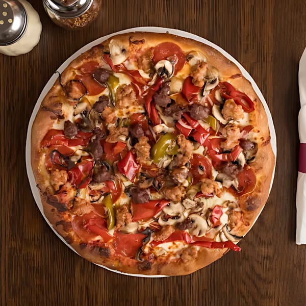 Overhead view of a supreme pizza with pepperoni, sausage, peppers, and mushrooms on a wooden table.